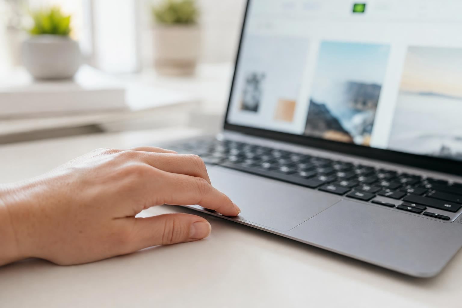 Main posée sur un pavé tactile devant une interface floutée